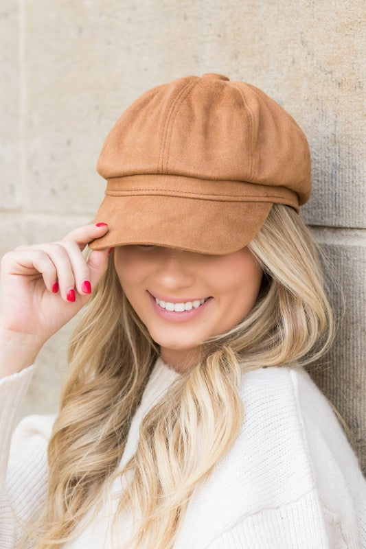Camel faux suede newsboy cap with structured bill worn by model adjusting brim