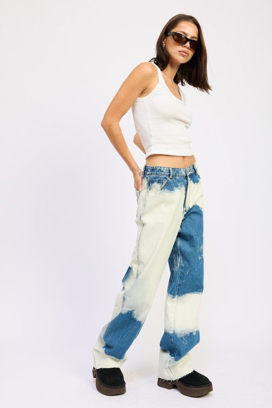 Side view of AVAH tie-dye washed denim jeans styled with tank and sunglasses