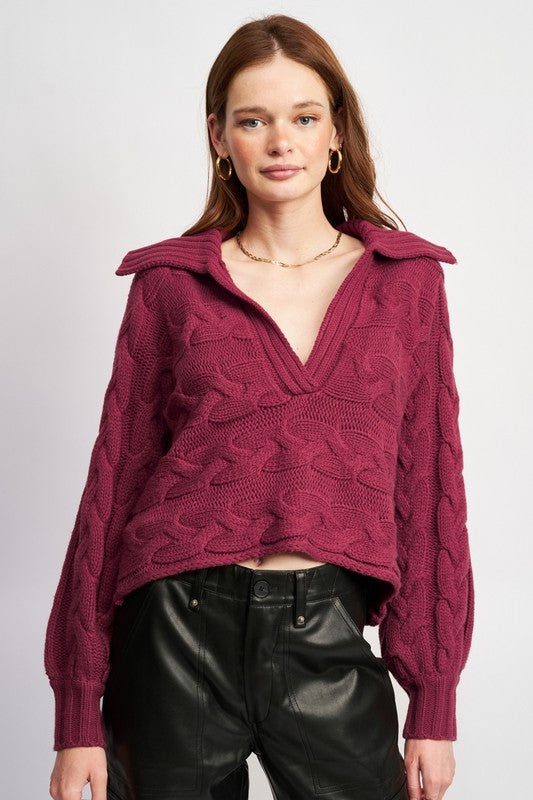 Woman wearing a burgundy-knit sweater with a deep V-neckline and foldover collar, front view.