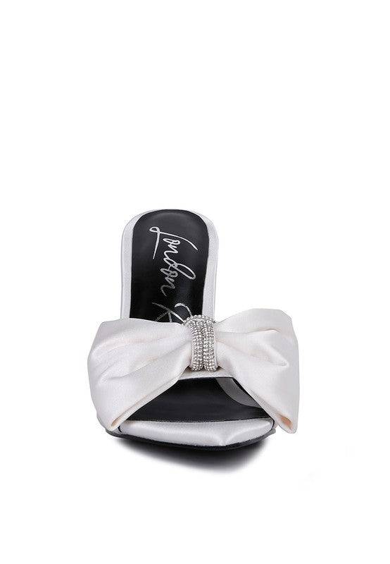 Front view of white satin heel showing oversized bow and rhinestone center