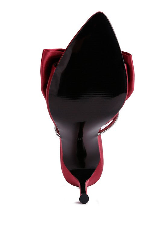 View of sole of burgundy satin heel showing oversized bow and rhinestone center