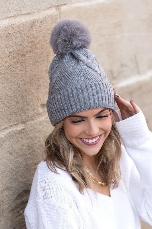 Grey knit winter hat with faux fur pom, front view