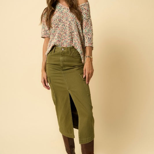 Front view of model wearing olive cargo denim midi skirt with floral top and brown boots.