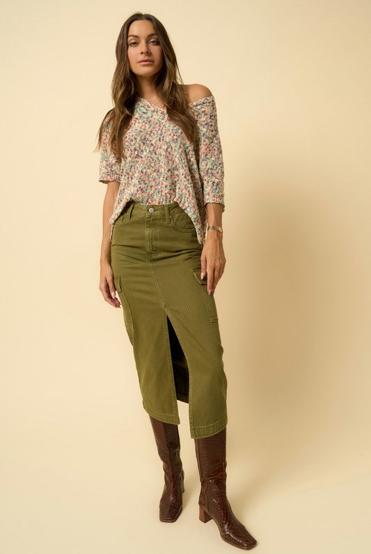 Front view of model wearing olive cargo denim midi skirt with floral top and brown boots.