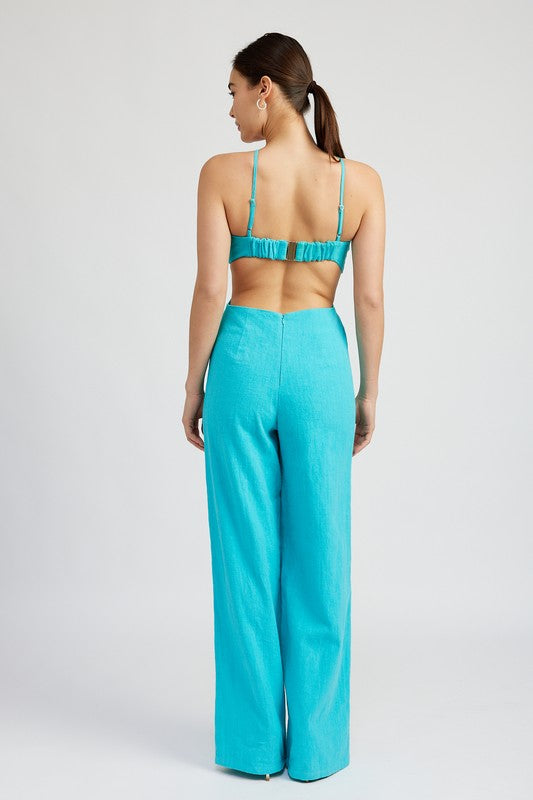 Back view of model showing open back and adjustable straps on turquoise jumpsuit