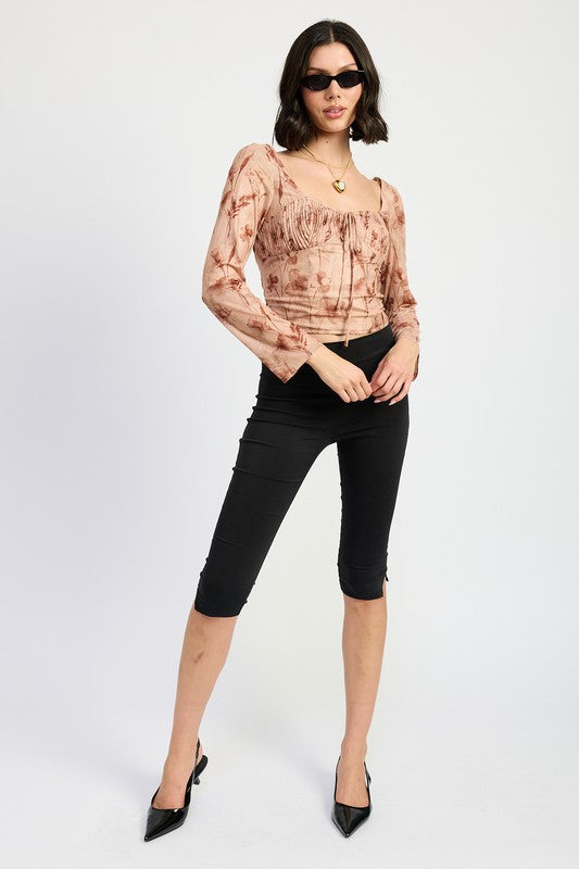 Full front view of model wearing long sleeve floral top styled with black capri pants and kitten heels