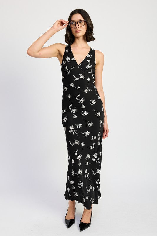 A model wearing a black maxi dress with a floral print, posing against a white background.