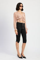 Blush plaid ruched long sleeve top with tie-front, paired with high-waist black pants and heels.