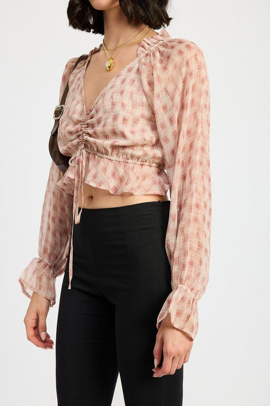 Side view of blush plaid ruched crop blouse with adjustable drawstring and ruffled hem.