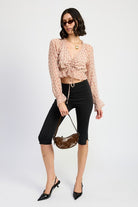 Model in blush plaid ruched crop top, black capri pants, pointed heels, and brown shoulder bag.