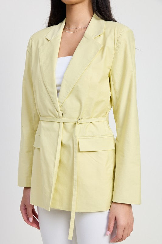 Close-up of blazer’s structured flap pockets and adjustable waist tie in sage green