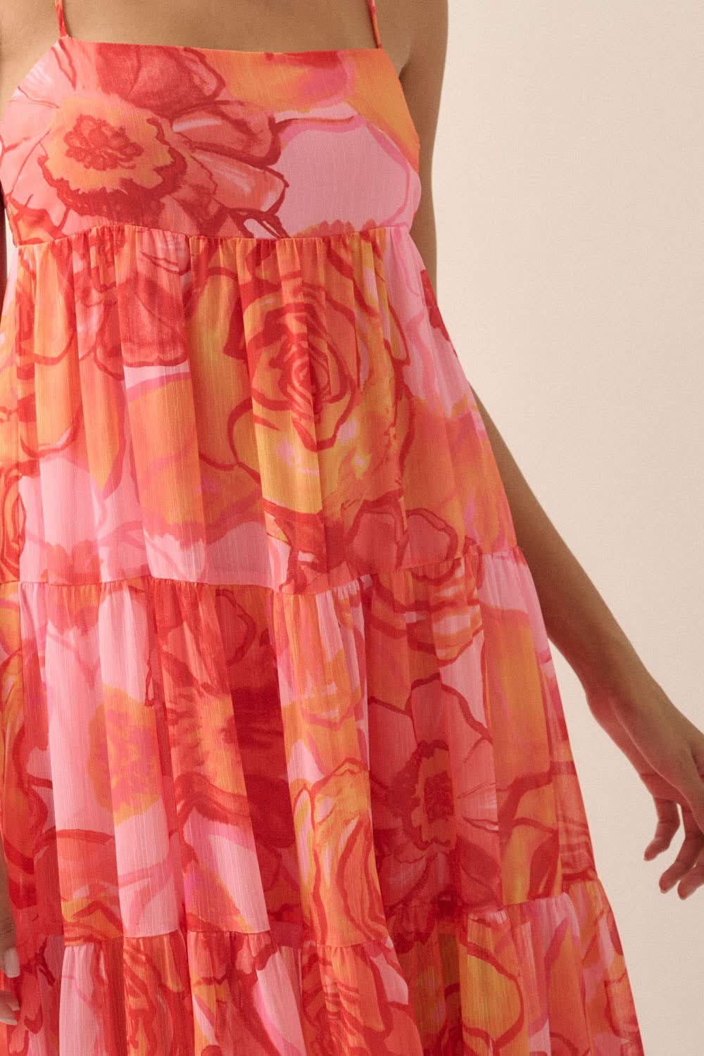 Close-up of the Rosewood Dawn Floral Maxi Dress showing vibrant pink, orange, and red rose print with tiered chiffon fabric and delicate pleating.