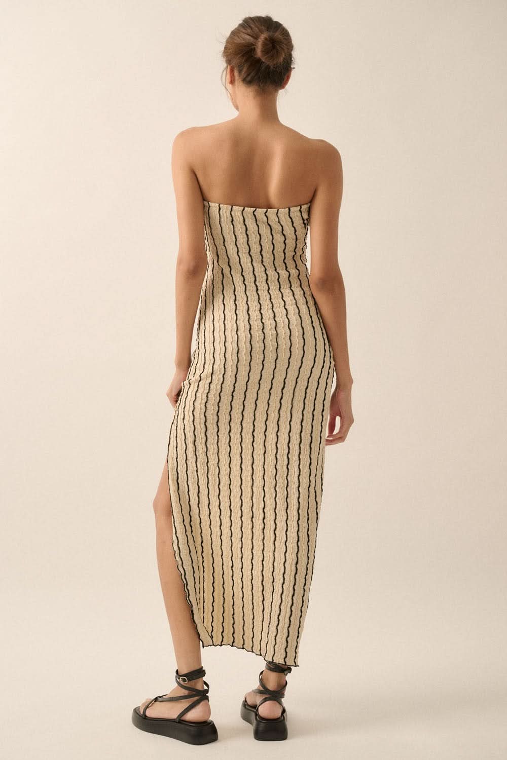 Back view of natural bodycon maxi dress showing low-back silhouette and vertical stripes.