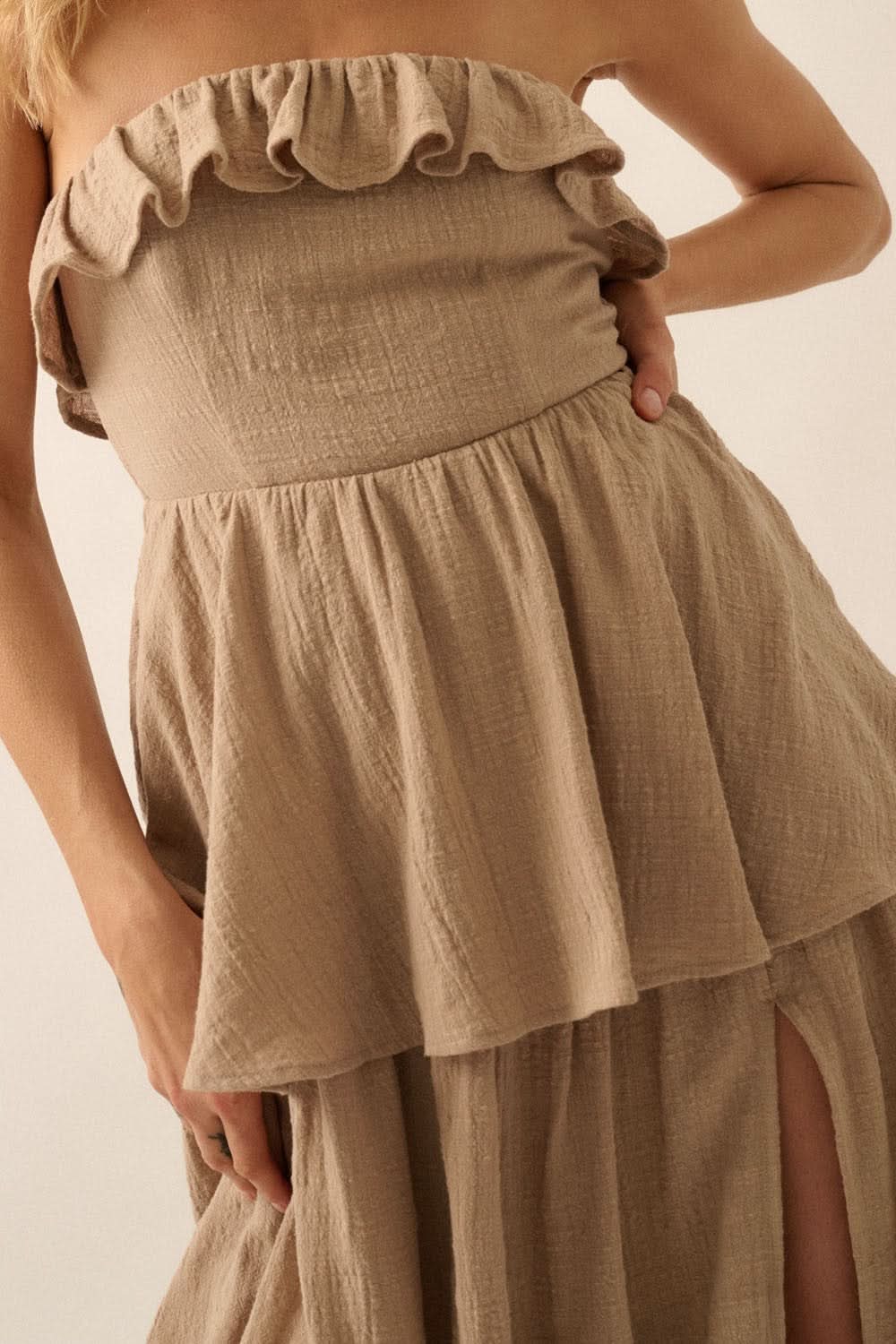 Close-up of the ruffled bodice and tiered skirt texture of taupe strapless maxi dress.