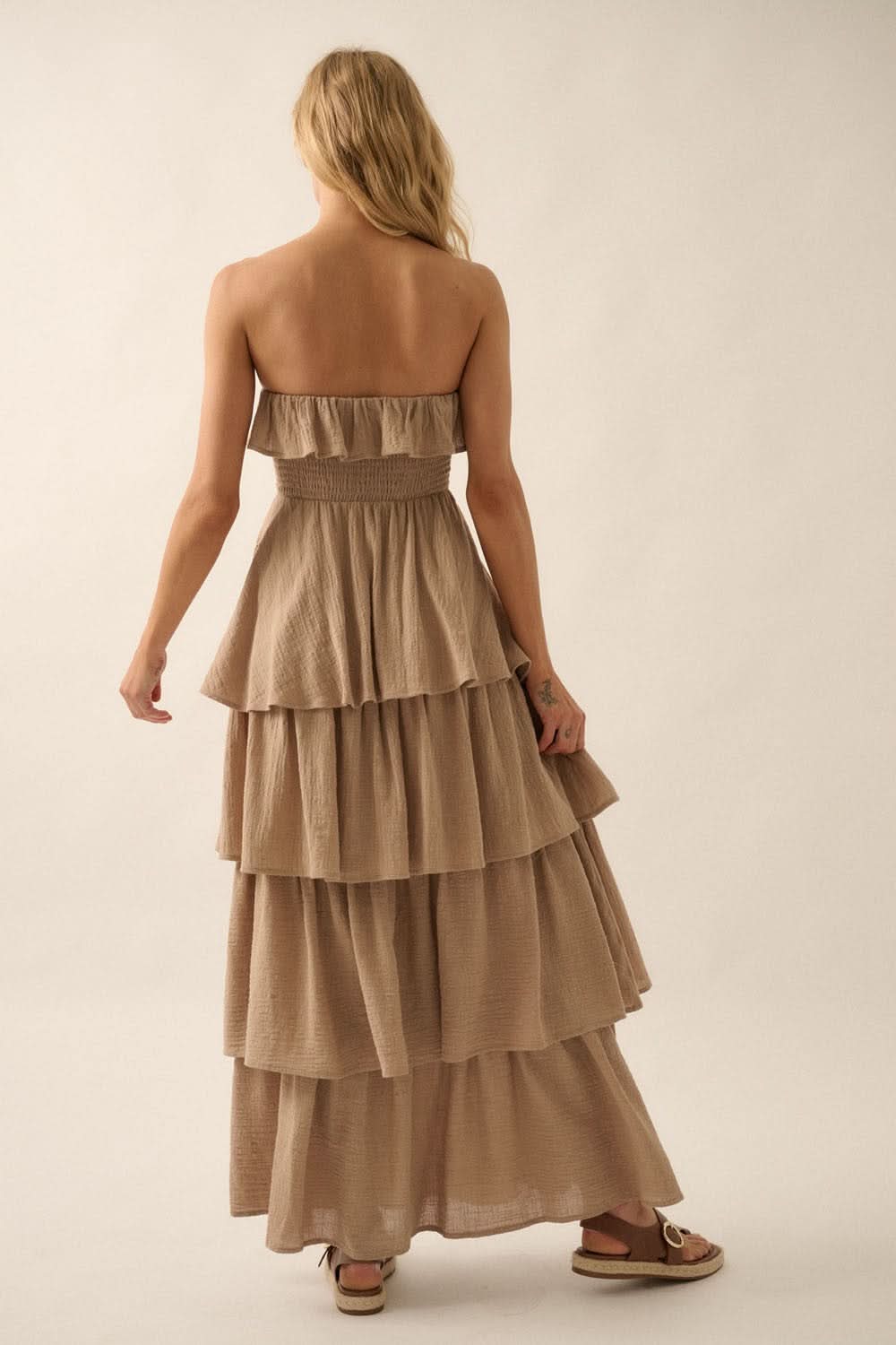 Model showing back smocking and layered skirt of taupe maxi dress with bare shoulders.