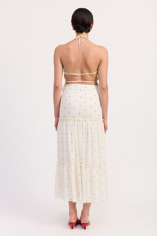 Side profile of tiered ivory maxi skirt with halter top and red sandals