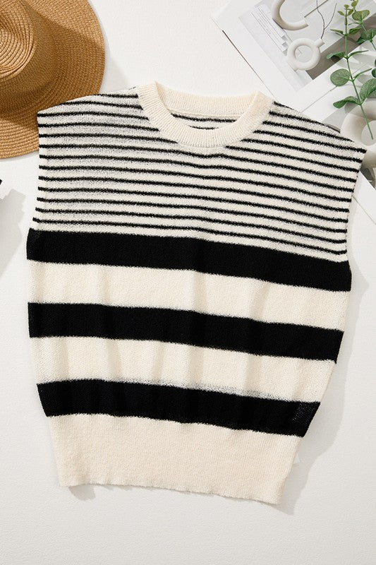 Flat lay of sleeveless striped knit sweater next to straw hat and greenery