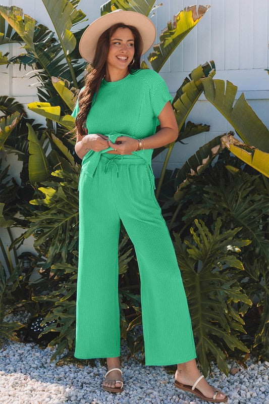 Green knit lounge set with top and pants, worn with sun hat.