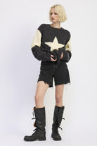 side view of oversized star knit styled with black shorts and boots