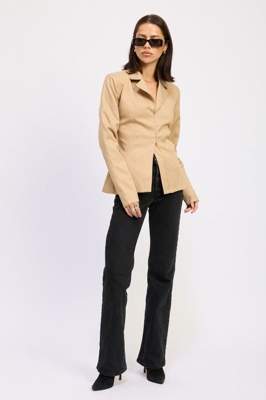Full-body view of model wearing camel sculpted blazer with black trousers and heeled boots.