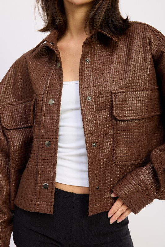 Close-up of AVAH brown textured cropped jacket showing snap button closure and dual flap chest pockets.