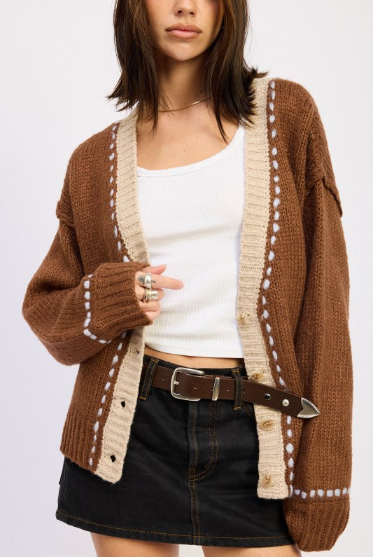 Close-up of brown two-tone knit cardigan showing cream border and button detail.