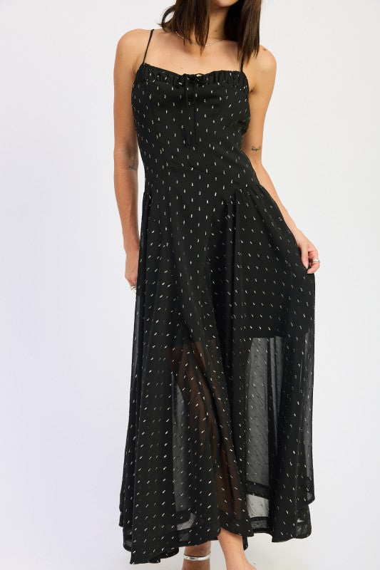 Black maxi dress with sheer dotted overlay and flowing A-line skirt, model holding hem to show movement-AVAH