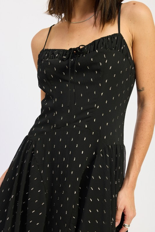 Detailed view of black maxi dress showing ruched straight neckline with tie accent and delicate dotted pattern
