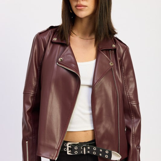 Model wearing burgundy faux leather moto jacket over white tank and black shorts.