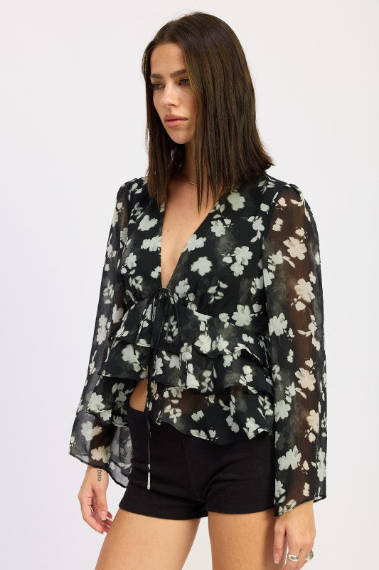 Side view of black floral blouse styled with shorts and silver handbag.