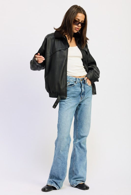 Full-body view of model wearing black vegan leather bomber jacket, white tank, and straight-leg light wash jeans.