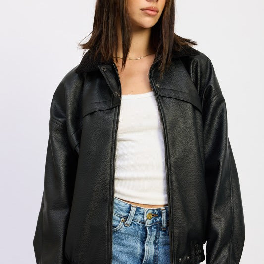 Model wearing black vegan leather bomber jacket with sherpa collar, styled with white tank and light wash jeans.