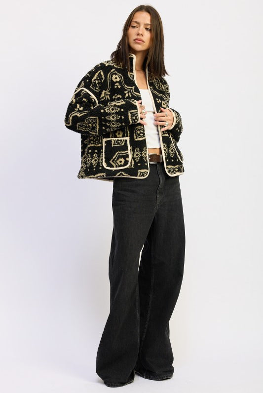 Side angle of patterned sherpa jacket layered over white top and jeans.