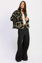Side angle of patterned sherpa jacket layered over white top and jeans.