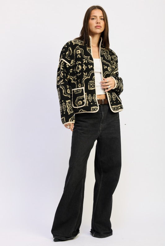 Front angle of patterned sherpa jacket layered over white top and jeans.