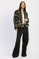 Front angle of patterned sherpa jacket layered over white top and jeans.