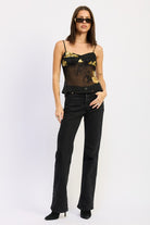 model wearing black and gold floral cami with sunglasses and black pants