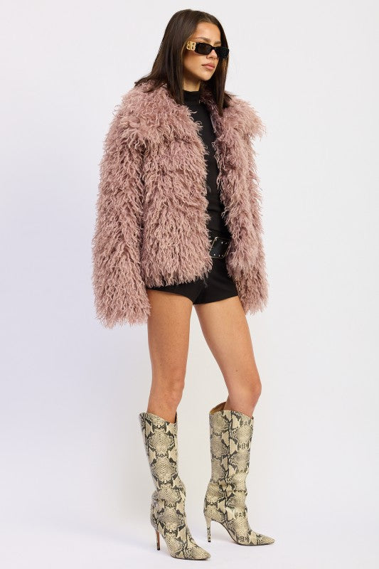 Side profile of the mauve textured coat with relaxed sleeves and tall snakeskin boots.