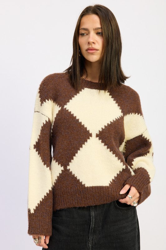 Model wearing brown and cream argyle knit sweater with crew neckline and relaxed fit, styled with black denim.-AVAH