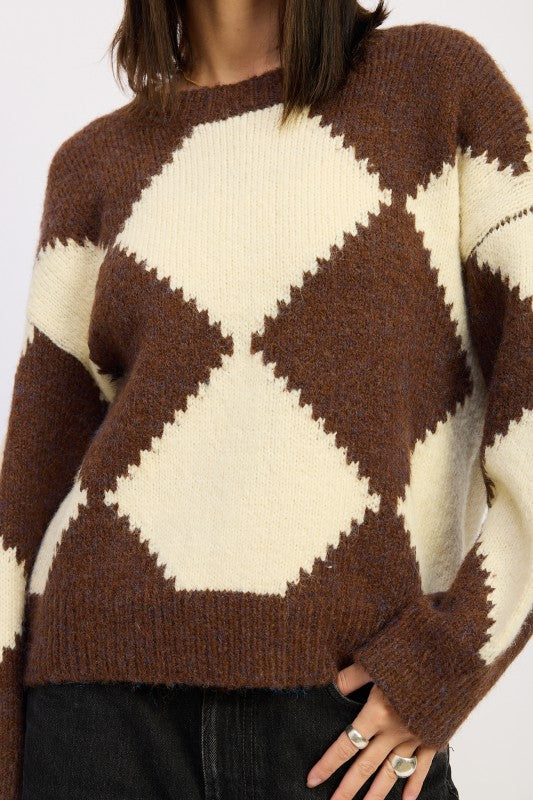 Close-up of argyle sweater showing soft knit texture in brown and cream diamond pattern with ribbed crew neckline.