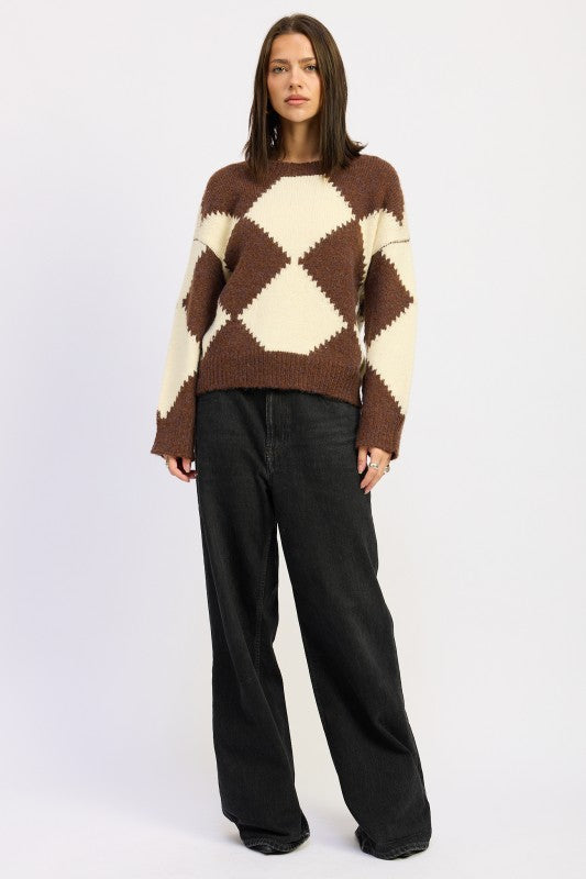 Woman in oversized argyle sweater with cream and brown diamond pattern, paired with wide-leg black jeans for a modern casual look.-AVAH