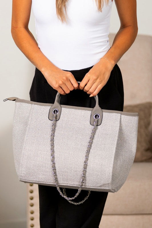 Gray canvas tote bag with silver chain shoulder strap and structured silhouette