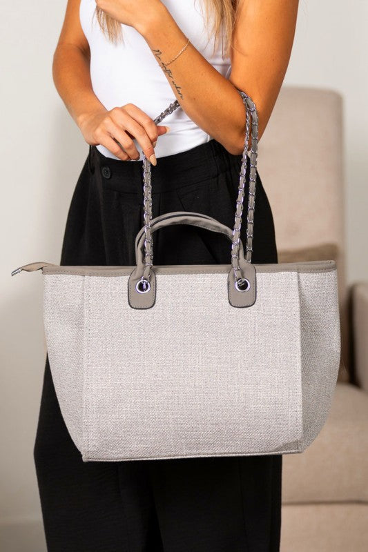 Gray structured canvas tote featuring silver chain shoulder strap and zip top closure