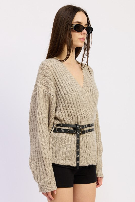 Side angle of warm grey ribbed sweater showing relaxed sleeve and belted waist