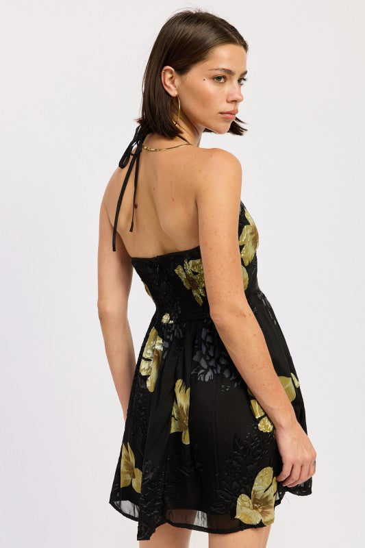 Back view of black floral halter mini dress with open-back tie detail