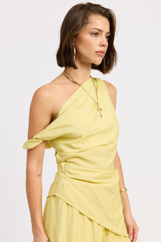 Woman wearing a pale yellow one shoulder asymmetrical top with black stripe against a white background