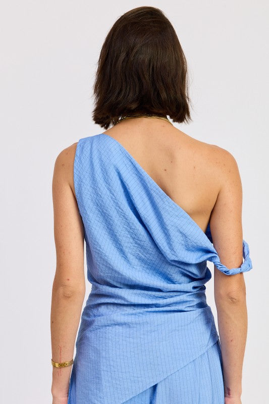 Woman wearing a blue one shoulder asymmetrical top with black stripe against a white background