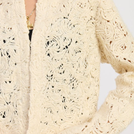 Close-up of Ivory Reverie Textured Cropped Jacket showing swirl knit pattern and soft cream fabric.