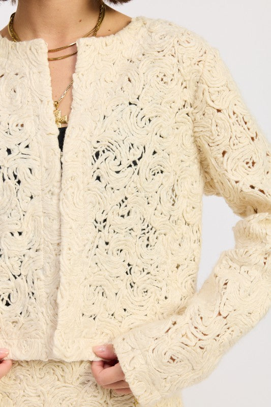 Close-up of Ivory Reverie Textured Cropped Jacket showing swirl knit pattern and soft cream fabric.