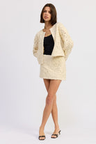 Model wearing Ivory Reverie Textured Mini Skirt and matching jacket in cream with black heels.